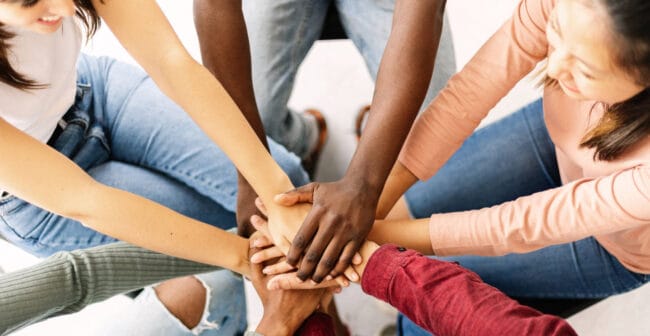 Menschen legen Hände aufeinander als Zeichen des Zusammenhaltes.